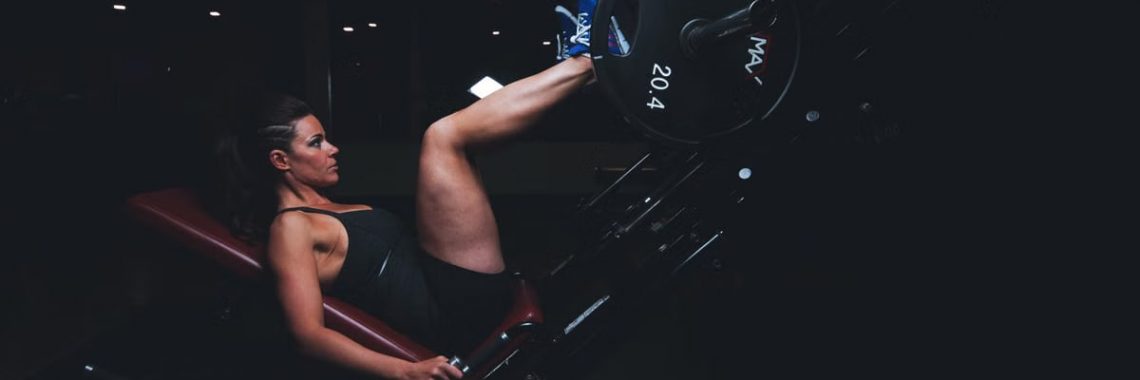 A woman engages in an intense leg press workout at the gym, showcasing strength and fitness.